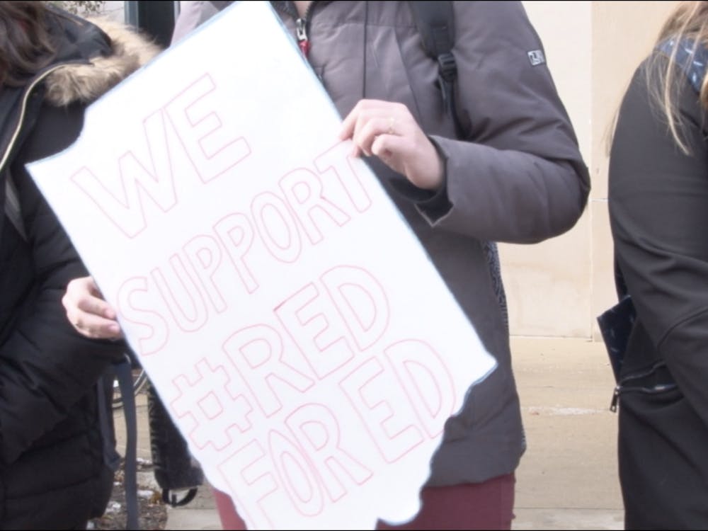 A Ball State student holds a signs at the Red for Ed walk out on campus that says "we support Red for Ed."