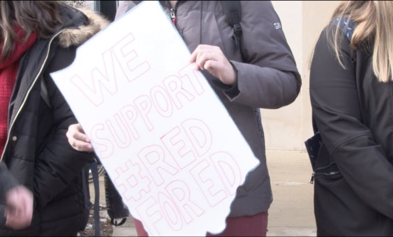 A Ball State student holds a signs at the Red for Ed walk out on campus that says "we support Red for Ed."