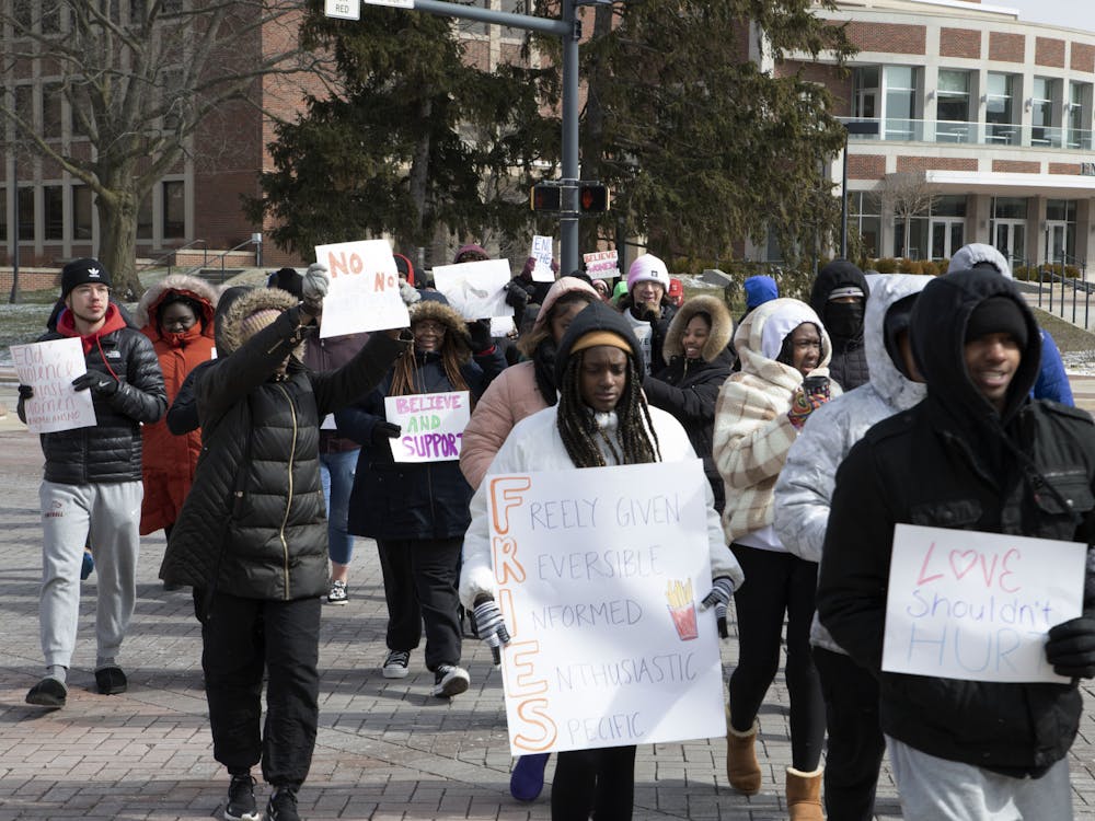 Protesters cross the scramble light holding signs during the Walk A Mile In Her Shoes event March 18. The event was hosted by Black Women’s Voices. Olivia Ground, DN