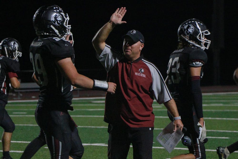 Wes-Del assistant football coach Daniel Henson high-fives junior running back Brock Nauman Oct. 4 during a game against Park Tudor at Wes-Del Middle/High School. Wes-Del won 72-45. Zach Carter, DN