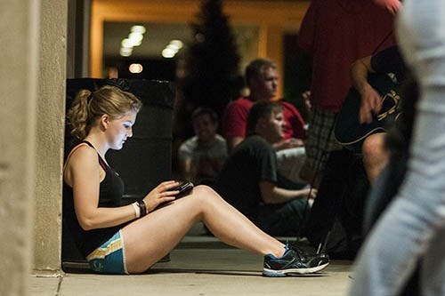 Junior music performance major Tony Zinich plays a friend's guitar as he waits for tickets. DN PHOTO JONATHAN MIKSANEK