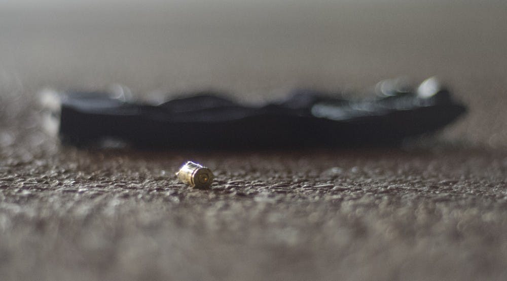 A shell casing lies next to a glove in the parking lot of the Phillips gas station on North Reserve Street and West University Avenue. Police were dispatched to the area after reports of shots fired in what was an armed robbery attempt. DN PHOTO COREY OHLENKAMP
