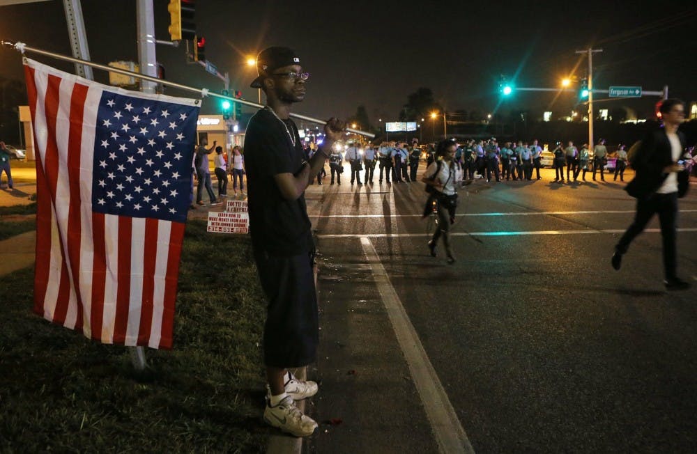 A protester watches the confrontation between the police and demonstrators on Monday in Ferguson, Missouri. A peace rally is planned for Sunday afternoon on campus to show support for those protesting the police brutality in Ferguson. MCT PHOTO