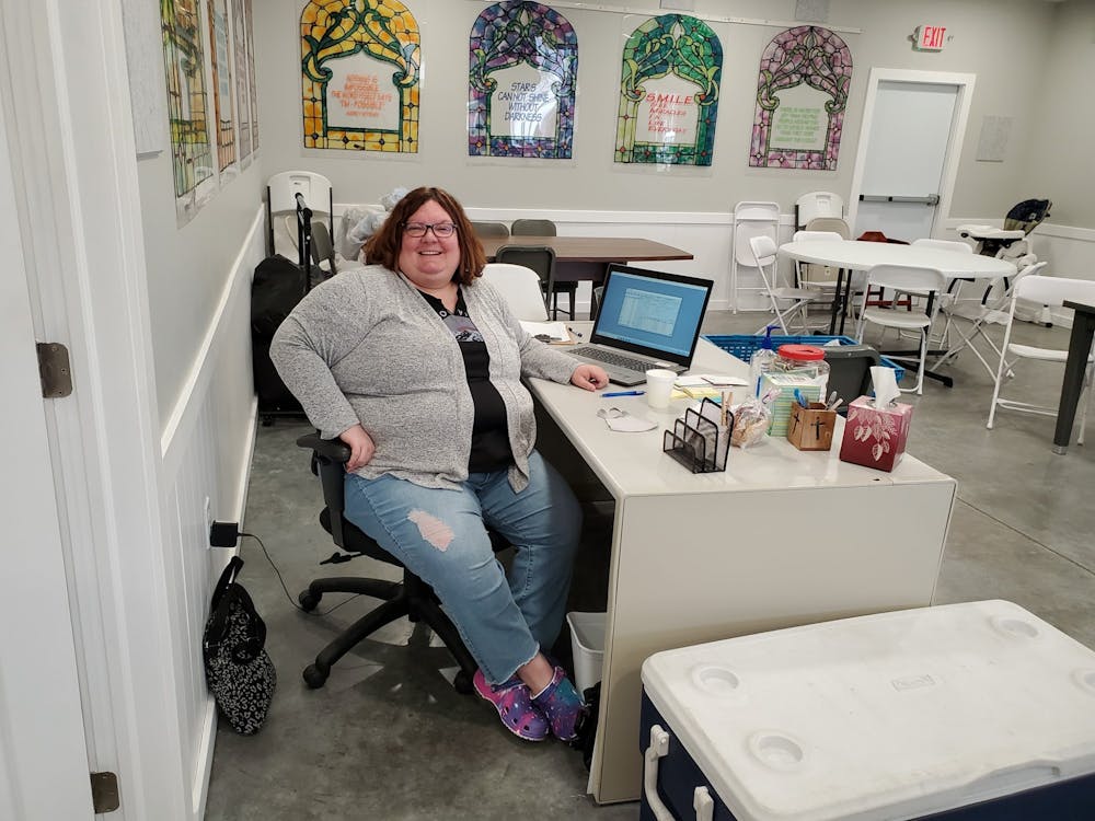<p>Toni Werner sits at a desk at Warm a Heart ministry in Waterloo. Werner is a 1999 Ball State alumna who taught for 23 years before becoming director of the ministry. <strong>Warm a Heart ministry, Photo Courtesy</strong></p>