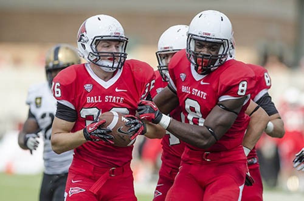 Jordan Williams hands the ball off to a fellow player after Ball State seals the victory in the fourth quarter against Army on Sept. 7. Williams continues to make the most of his opportunities with the first team. DN PHOTO COREY OHLENKAMP