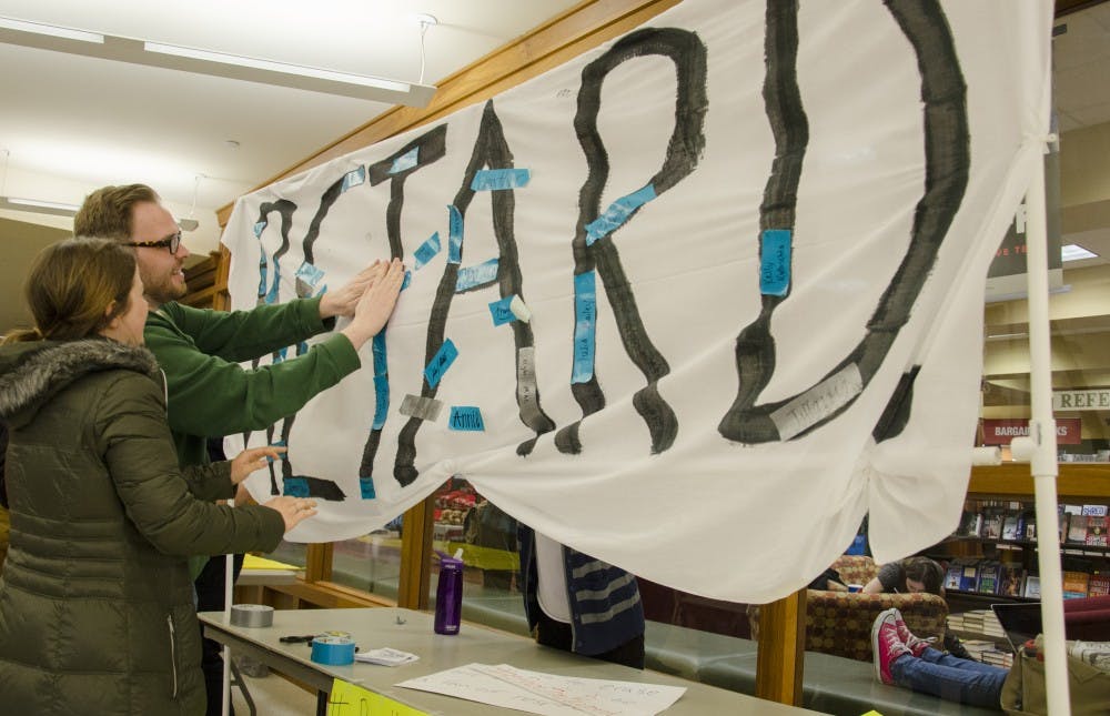 Alumnus Andy Roets and junior art education major Taylor West place a piece of tape with their name on in to support the end of the R word. DN PHOTO BREANNA DAUGHERTY