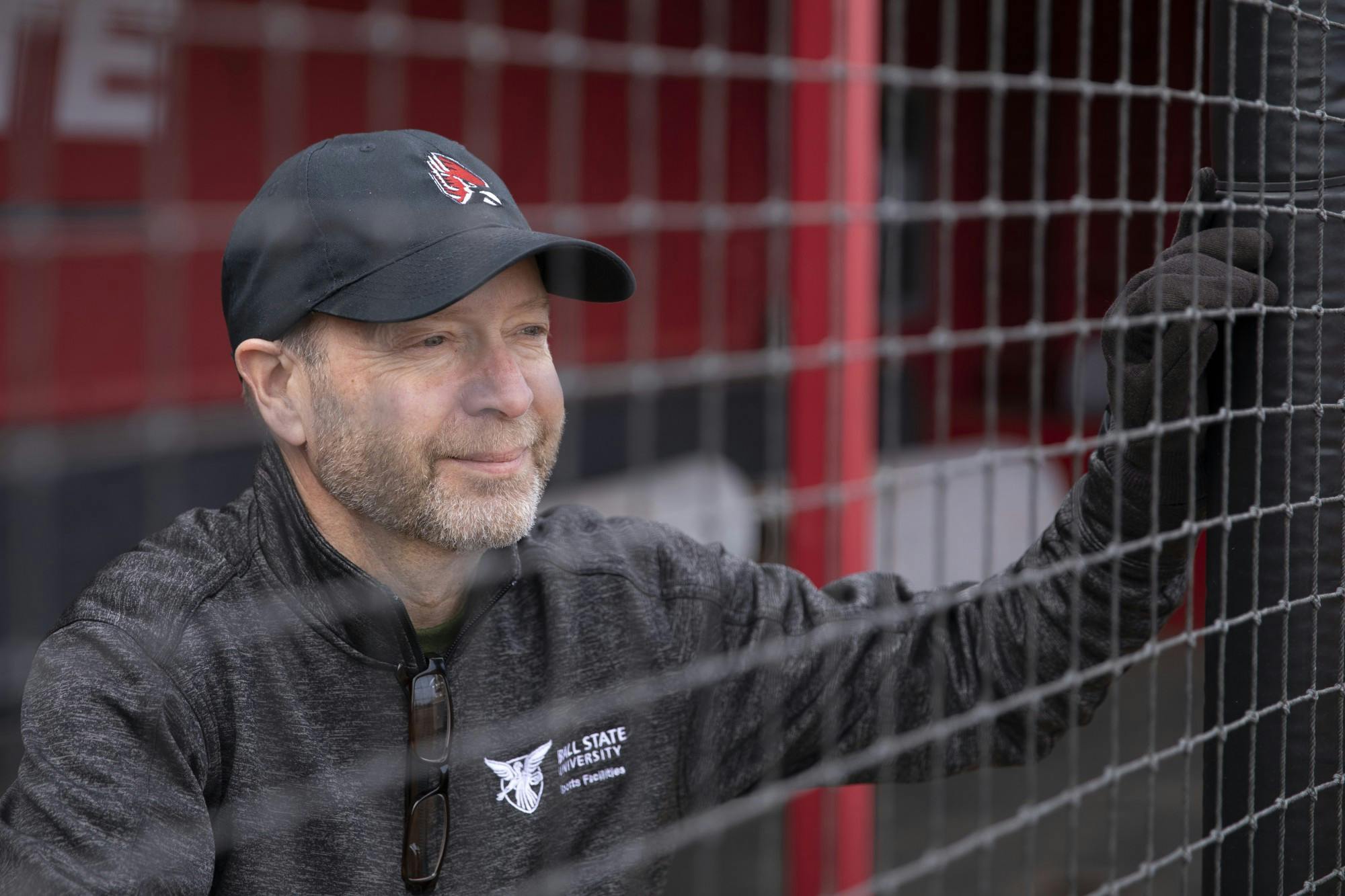 Phil Clay, manager of physical education athletic grounds and facilities supervises looks through the netting of the dugout March 24, 2021, at Ball Diamond at First Merchants Ballpark Complex. Clay is in charge of the facilities for the outside athletic fields including softball, baseball, soccer and field hockey. Jacob Musselman, DN