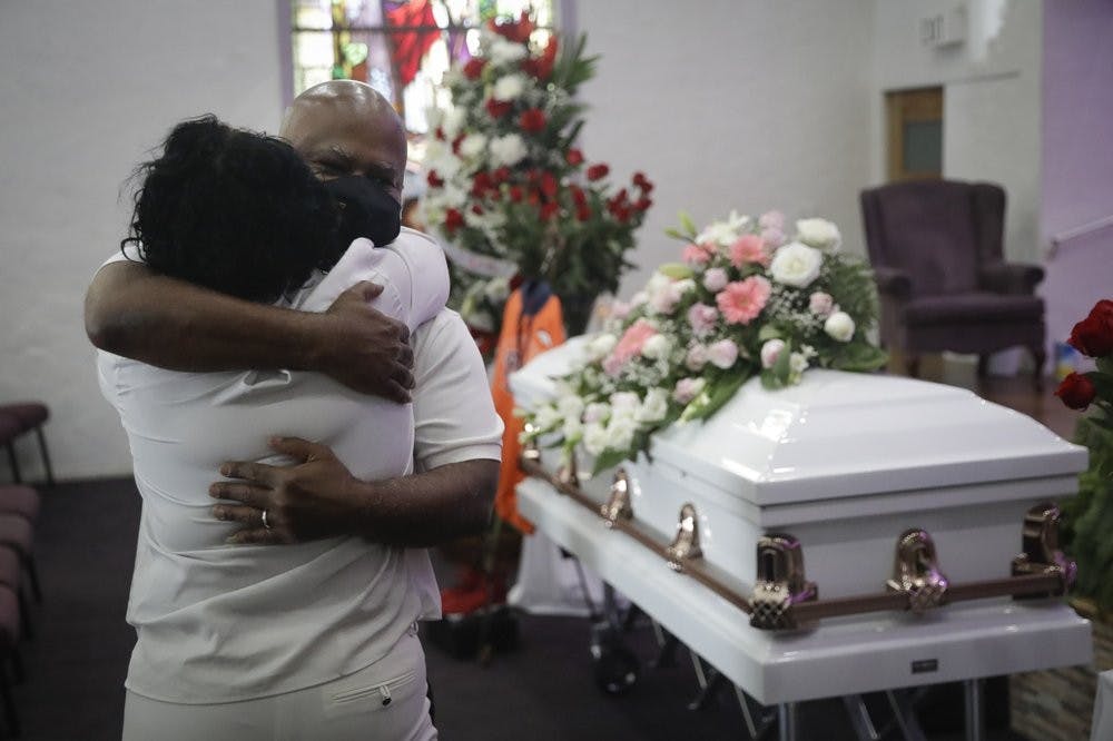 FILE - In this July 21, 2020, file photo, Darryl Hutchinson, facing camera, is hugged by a relative during a funeral service for Lydia Nunez, who was Hutchinson's cousin at the Metropolitan Baptist Church in Los Angeles. Nunez died from COVID-19. (AP Photo/Marcio Jose Sanchez, File)