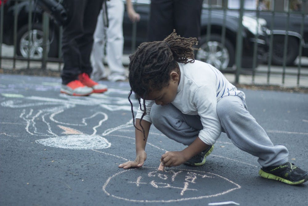 Levi Donati draws with chalk at Arts Walk on October 2nd. The event featured Yart, where many artists sold their work. DN PHOTO EMMA ROGERS