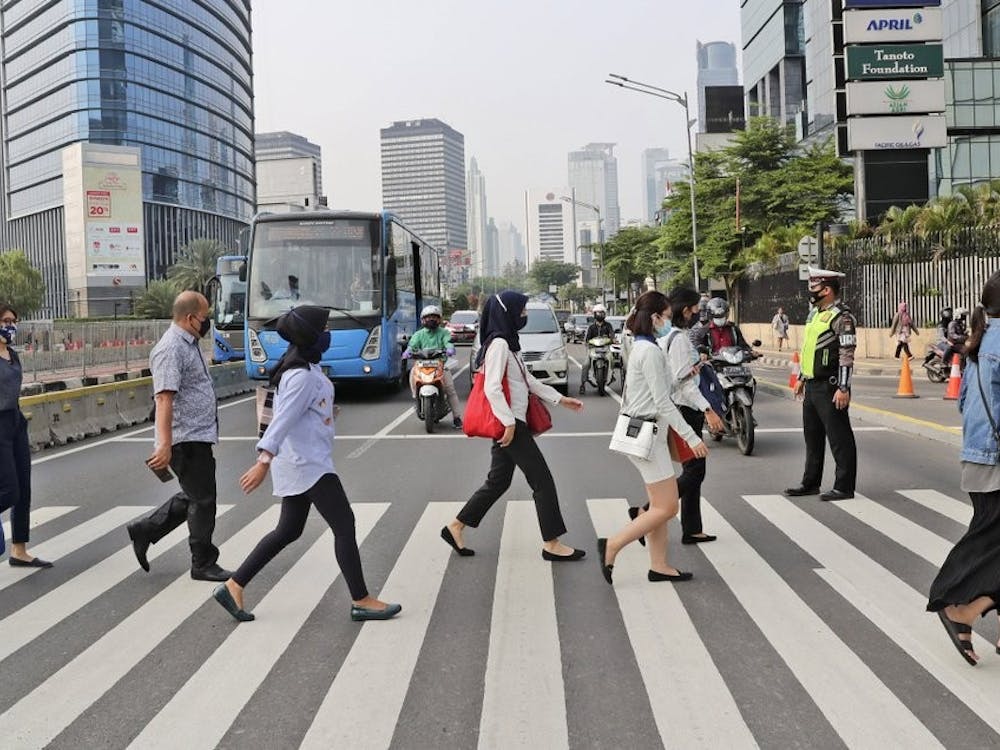 People, wearing a face mask as a precaution against the new coronavirus outbreak, walk on a pedestrian crossing at the main business district in Jakarta, Indonesia, Monday, Sept. 14, 2020. Indonesia's capital on Monday begins to reimpose large-scale social restrictions to control a rapid expansion in the virus cases. (AP Photo/Tatan Syuflana)