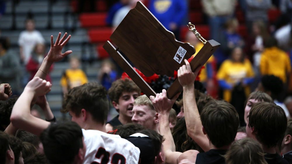 A Wapahani boys' basketball player holds the 2A semistate trophy March 16 after a game against Fort Wayne Christian Blackhawk at Lafayette Jefferson High School. It is the first semistate title in program history. Zach Carter, DN.