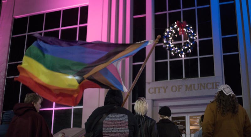 Beth McCollum listens to a speaker at City Hall, November 11th, 2024. City Hall is illuminated by lights matching the Transgender Pride Flag. Jeffrey Dreyer, DN