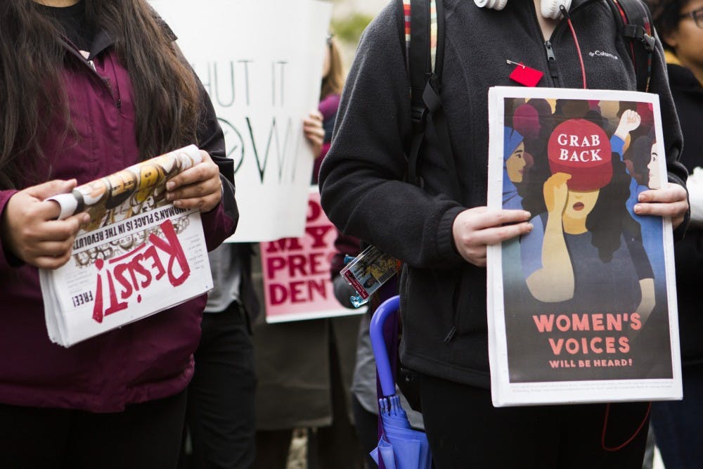Attendees of the Trump Resistance Rally hold various signs while listening to speeches outside of Bracken Library on Jan. 20. The rally was organized by several activist groups on campus to protest the inauguration of President Donald Trump. Emma Rogers // DN 