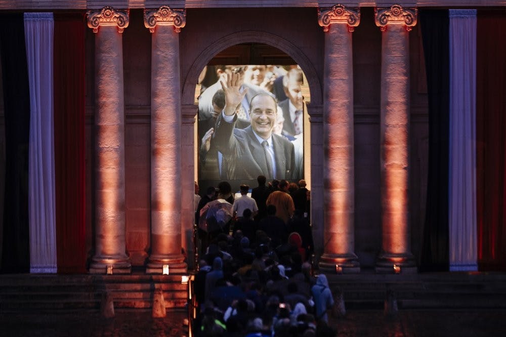 Members of the public queue as night falls at the Invalides monument to pay their respects to late French President Jacques Chirac, Sunday, Sept. 29, 2019 in Paris. Jacques Chirac will lie in state Sunday during a public ceremony at the Invalides monument, where France honors its heroes. A memorial service and private funeral are planned for Monday. (AP Photo/Kamil Zihnioglu)