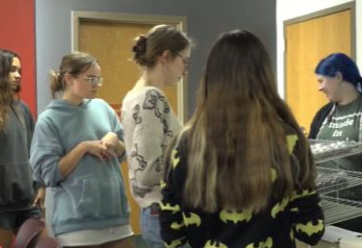 Students line the art table to grab supplies and the piece of art they want to create.