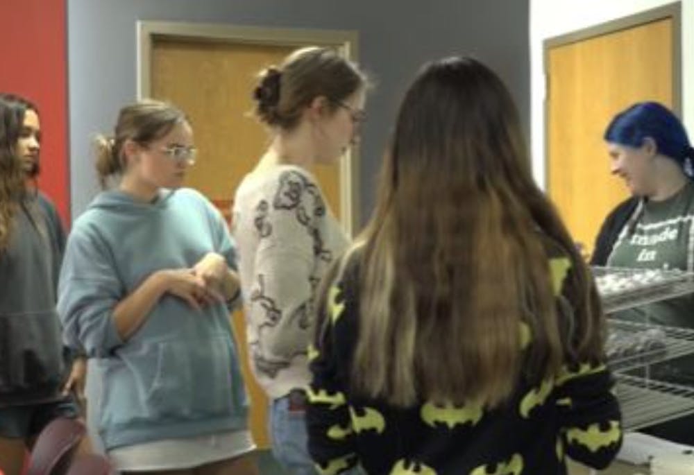 Students line the art table to grab supplies and the piece of art they want to create.