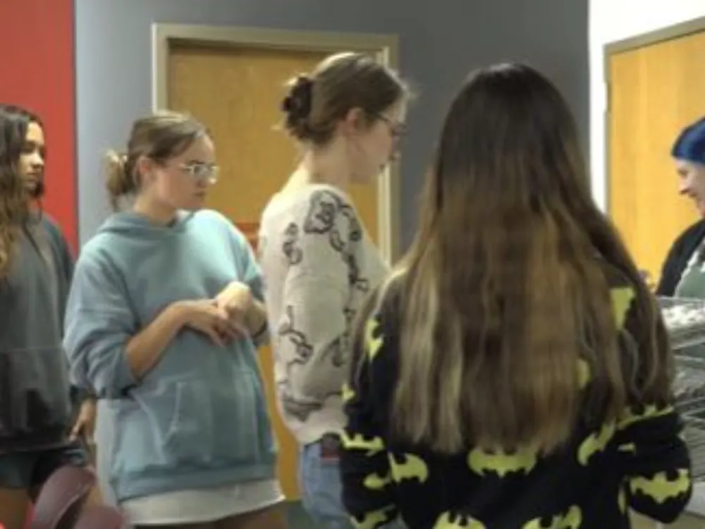 Students line the art table to grab supplies and the piece of art they want to create.