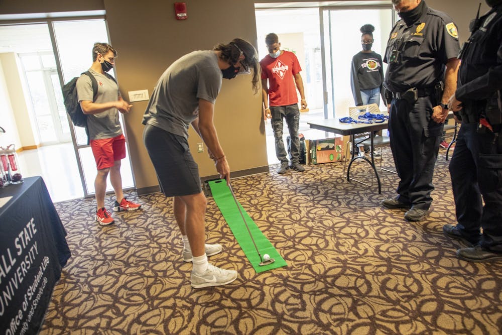 <p>Freshman chemical engineering major Issac Daniels plays mini golf with &quot;drunk goggles&quot; on, while onlookers watch in the L.A. Pittenger Student Center Oct. 20, 2021. The mini golf was stationed at the campus police table at the &quot;Save Your Beers For Another Day&quot; event. <strong>Hannah Amos, DN</strong></p>
