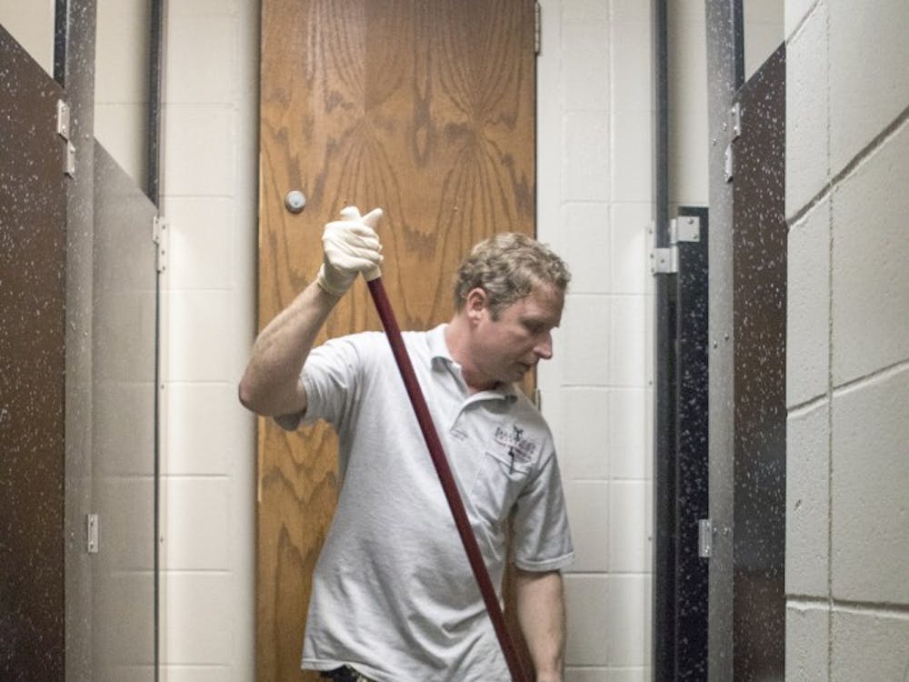 Custodian Greg Hobson mops and cleans one of the men's bathrooms on the LaFollette Complex's first floor.  Hobson has worked for the university for almost 30 years. DN PHOTO JORDAN HUFFER