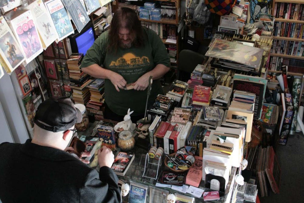 Derek Edwards helps a customer with his purchase at White Rabbit Bookstore in the Village. Edwards has had many regulars in his 22 years of business, and many new faces each year. DN PHOTO LOGAN WINSLOW