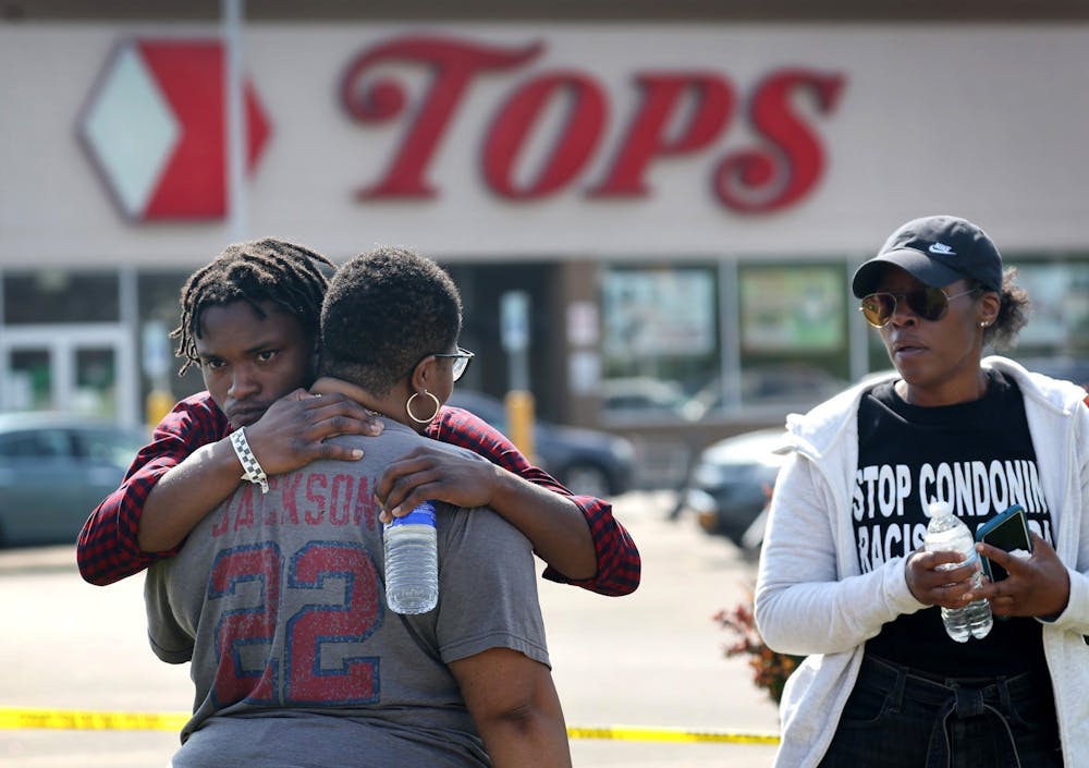 CREDIT: Tribune News Service- People gathered outside of Tops market embrace on May 15, 2022 in Buffalo, New York. Yesterday a gunman opened fire at the store, killing ten people and wounding another three. Suspect Payton Gendron was taken into custody and charged with first degree murder. (Scott Olson/Getty Images/TNS)