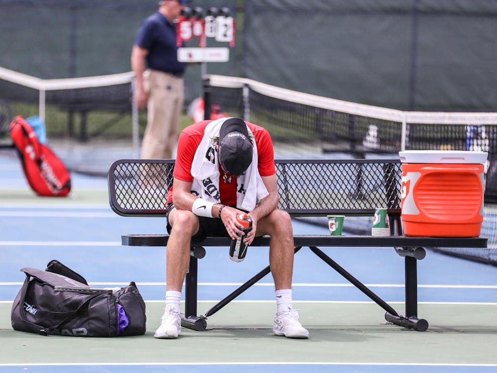 Fourth-year Vince Orlando sits on bench to rest after a singles match against Binghamton University on April 14 at the Cardinal Creek Tennis Center. Orlando won his first singles match. Katelyn Howell, DN.