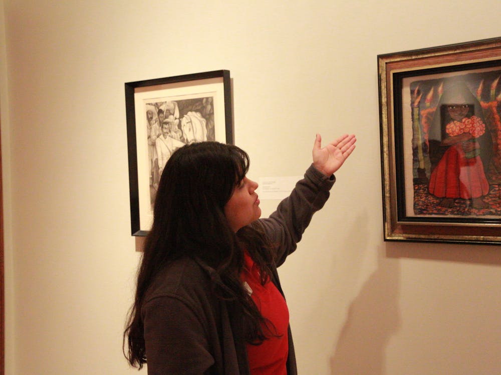 Jasmine Romero, museum docent, explains the details of artist Diego Rivera's "Niña con flores" Feb. 23, 2020. Romero pointed out the candles and flowers in the watercolor painting as inspired by the traditionally Hispanic day of remembrance Día de los Muertos. Brooke Kemp, DN