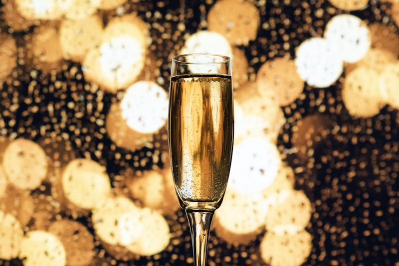 Champagne bubbles in a champagne flute as lights illuminate the room. Unsplash, Photo Courtesy
