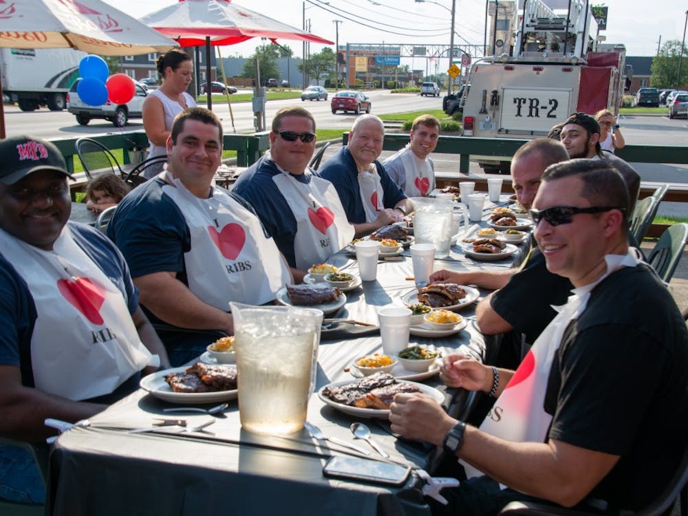 Members of the Muncie Fire Department (right) and Muncie Police Department (left) smile before beginning their fifth annual Battle of the Badges Sept. 18, 2018, at Texas Roadhouse in Muncie. Ten percent of every meal bought during the competition was donated to the charity of the winner's choosing. Leslie Gartrell,DN