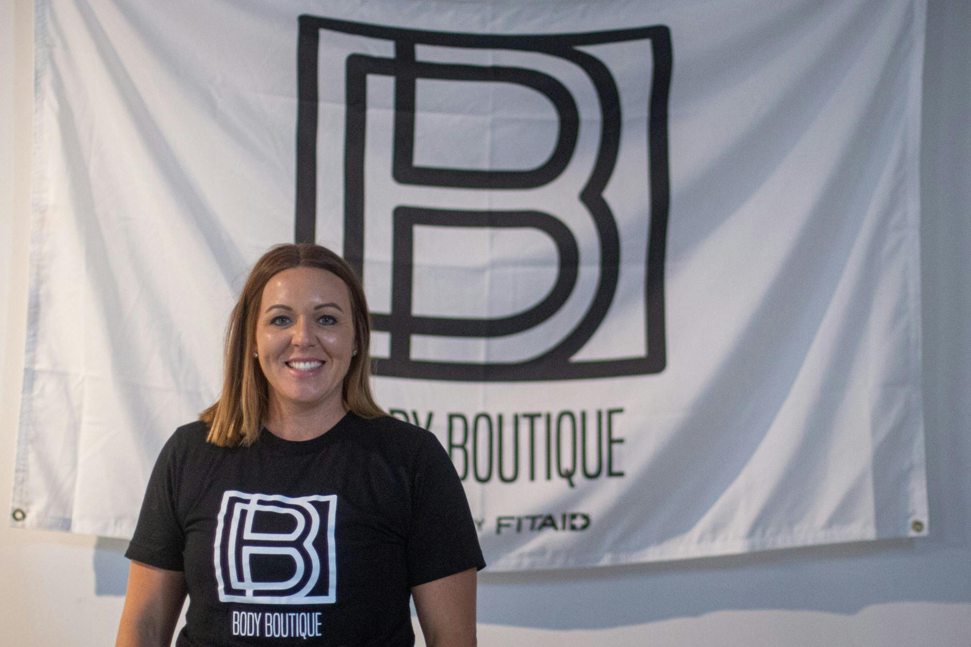 Brittney  Russell poses in front of a Body Boutique flag Sept. 10, 2020, at Body Boutique. Russell started Body Boutique out of a love for helping women reach their fitness goals. Demi Lawrence, DN