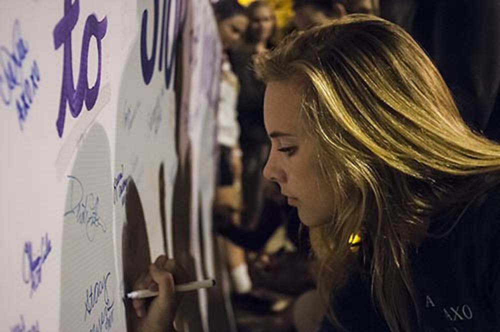 Junior psychology major Courtney Harris signs the board to show her support for victims of sexual assault and domestic violence. Alpha Omicron Pi and Alpha Chi Pi hosted the event on Oct. 3. DN PHOTO JONATHAN MIKSANEK