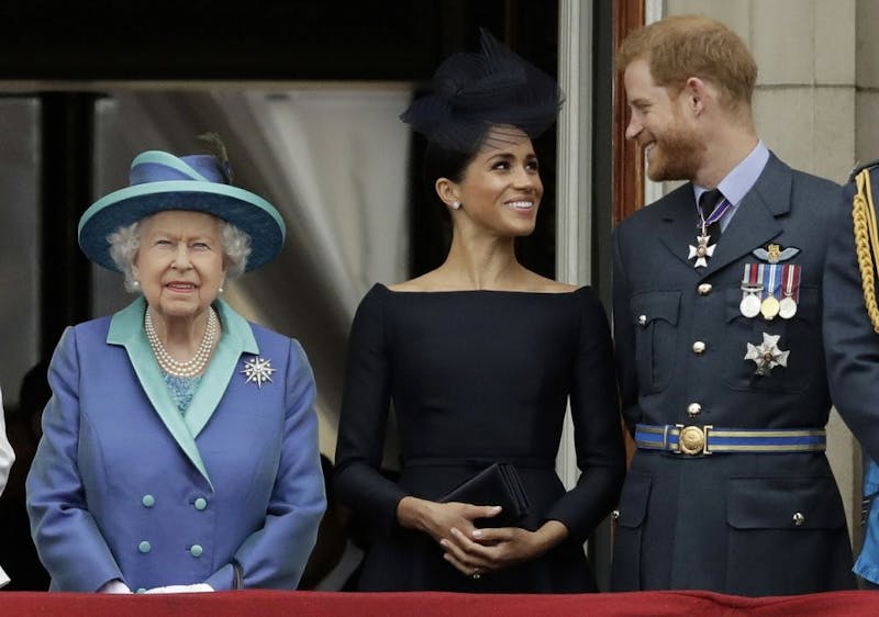 In this July 10, 2018, file photo Britain's Queen Elizabeth II, Meghan, Duchess of Sussex, and Prince Harry watch a flypast of Royal Air Force aircraft pass over Buckingham Palace in London. As part of a surprise announcement distancing themselves from the British royal family, Harry and his wife Meghan declared they will “work to become financially independent." (AP Photo/Matt Dunham, File)