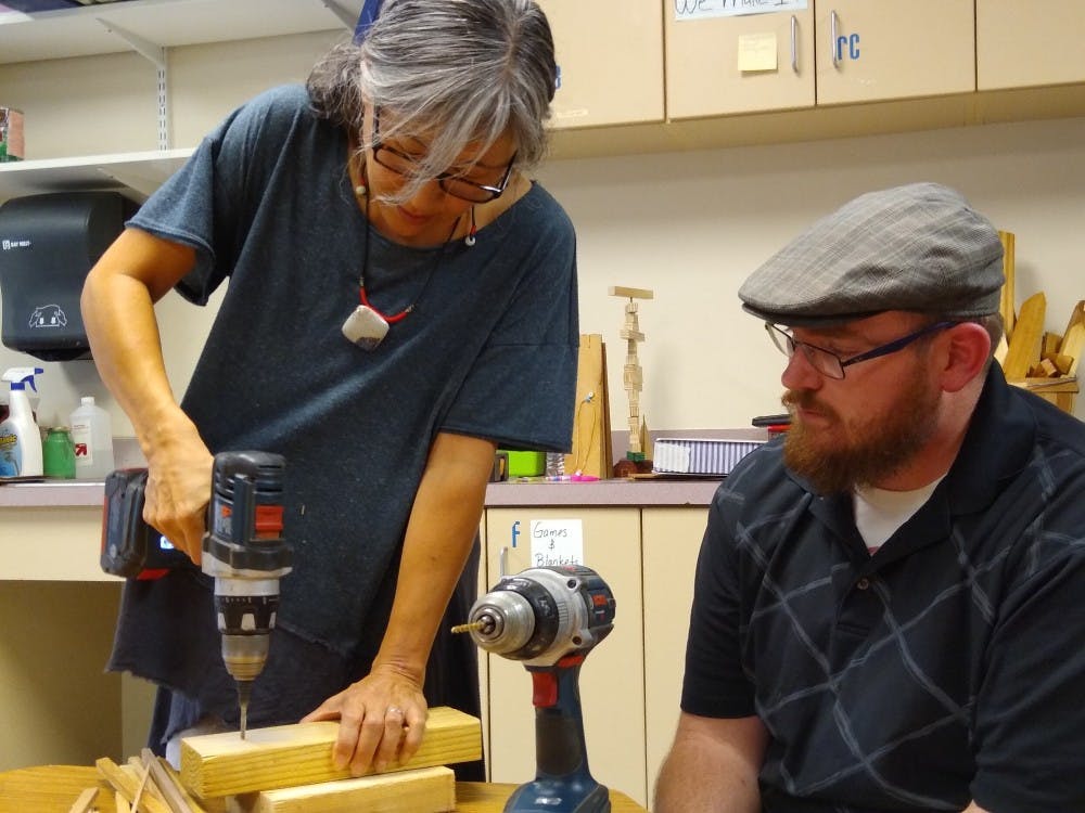 Janice Shimizu, assistant professor of practice at Ball State, and Mason Olson, alumni from the Ball State Architecture Program, demonstrate how to properly use a power drill to students. Every first Thursday of each month, Shimizu goes with assistants to help teach architecture to students at Motivate our Minds. Charles Melton, DN