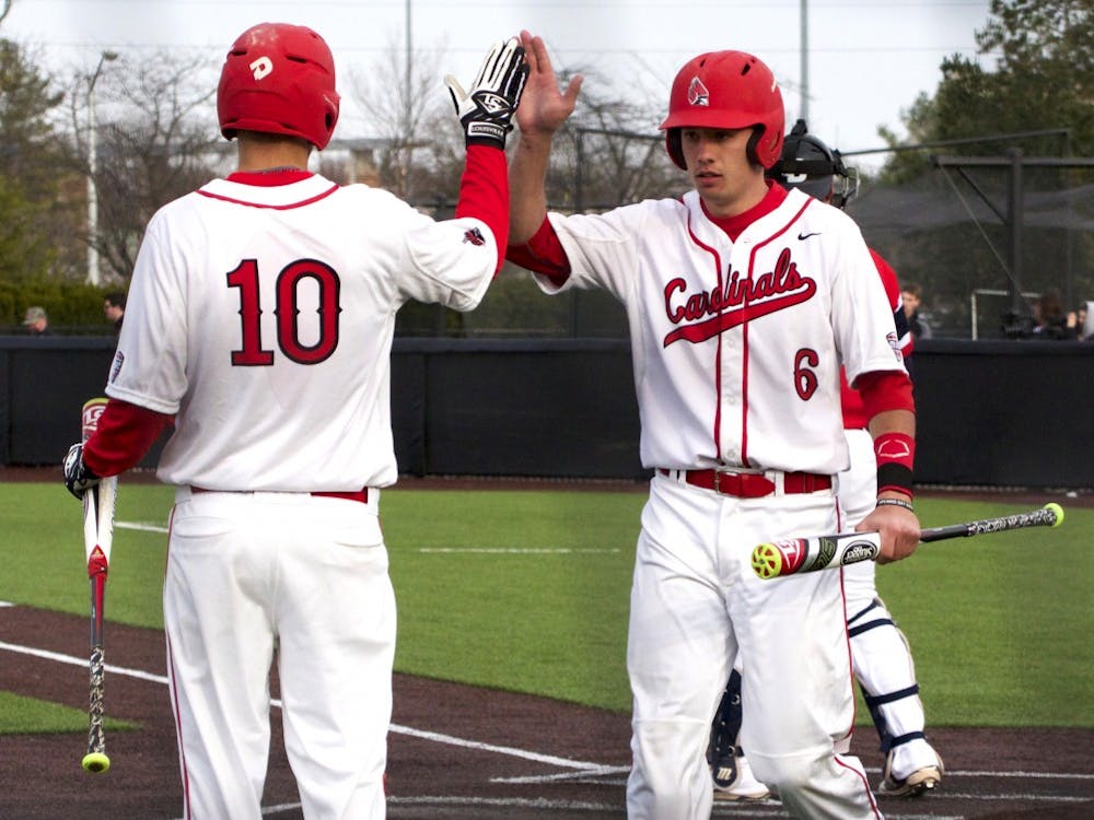 Ball State’s junior infielder Sean Kennedy congratulates junior infielder Alex Maloney on making it back to home base during the game against Dayton on March 18. DN PHOTO GRACE RAMEY