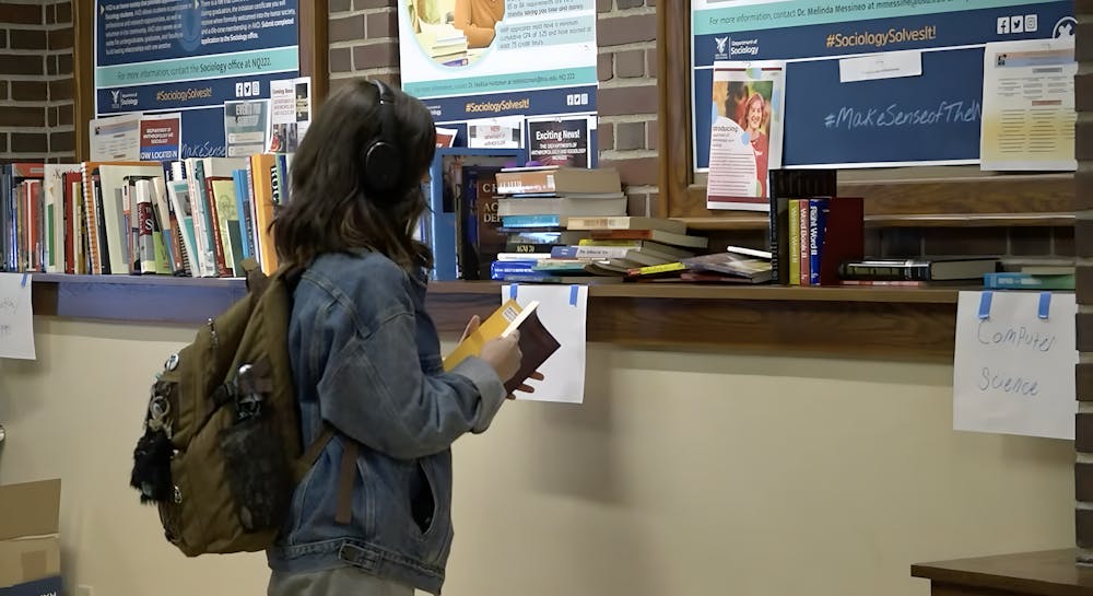 <p>A student peruses books at the BIG Booksale in the North Quad.</p>