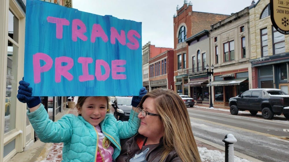 Hazel and her mother, Felicia Lewis, hold up a sign March 31 at the Transgender Day of Visibility event in downtown Muncie. The event was organized by East Central Indiana Trans Alliance. John Lynch, DN