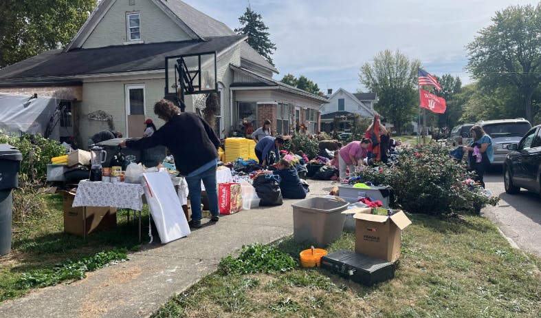 Community members pick up items from totes and tables.
