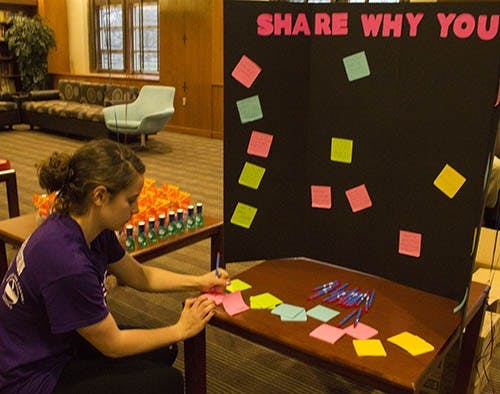 Sara McInerney writes a note for the “Share Why You Care” board in the Music Lounge at the L.A. Pittenger Center Tuesday evening. The event was originally scheduled to be in LaFollette Field, but had to be moved inside due to heavy rain. DN PHOTO TAYLOR IRBY