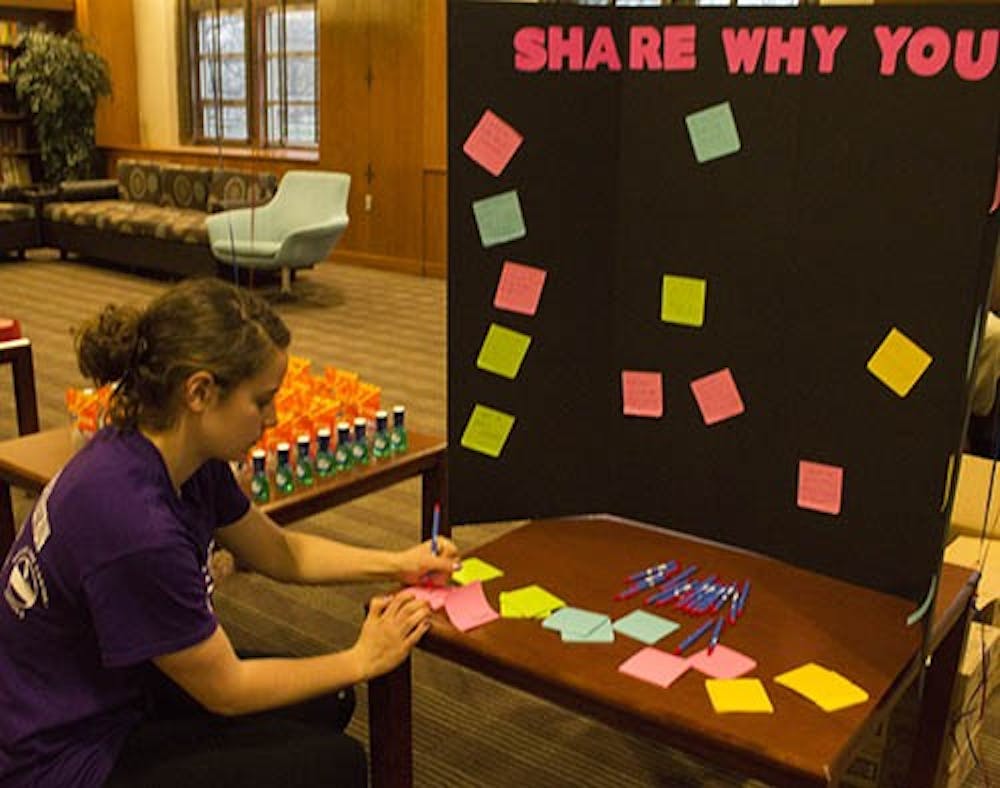 Sara McInerney writes a note for the “Share Why You Care” board in the Music Lounge at the L.A. Pittenger Center Tuesday evening. The event was originally scheduled to be in LaFollette Field, but had to be moved inside due to heavy rain. DN PHOTO TAYLOR IRBY