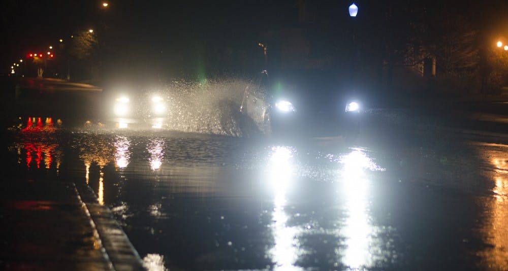 Cars drive down a partially flooded Wheeling Avenue after the storm on the evening of Nov. 17. The storm left large amounts of rainfall around the area. DN PHOTO BREANNA DAUGHERTY