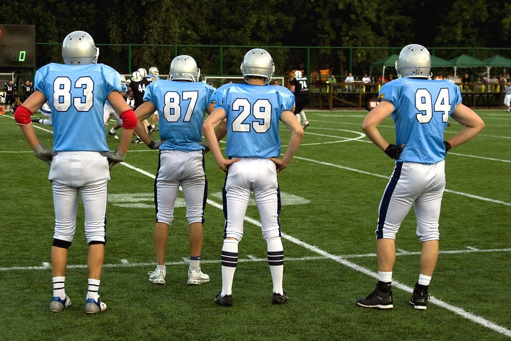American football players on sidelines at a game field.