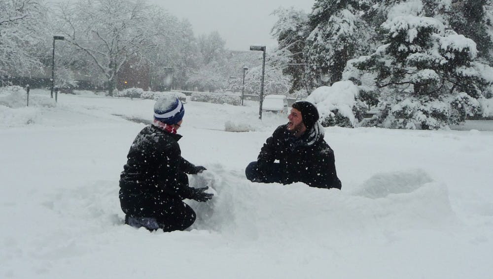 Gabe Weaver, a sophomore visual communications major and Katie Clark, a sophomore hospitality and food management major, crouch in the snow near Bracken Library. The two built the fort a few hours before the winter storm intensified. DN PHOTO SAM HOYT