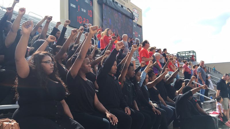 Students sit, raise fists during national anthem