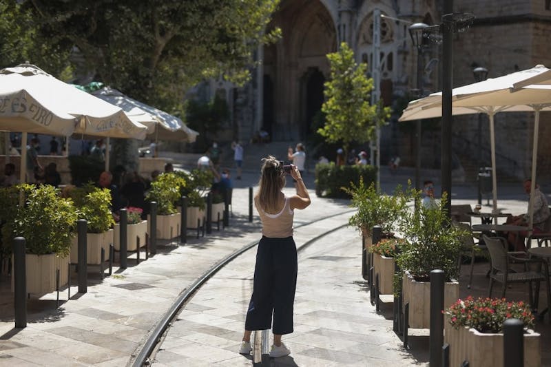 A tourist take photos in town of Sóller, in the Balearic Island of Mallorca, Spain, Monday, July 27, 2020. Britain has put Spain back on its unsafe list and announced Saturday that travelers arriving in the U.K. from Spain must now quarantine for 14 days. (AP Photo/Joan Mateu)