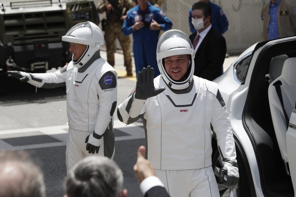 NASA astronauts Douglas Hurley, left, and Robert Behnken walk out of the Neil A. Armstrong Operations and Checkout Building on their way to Pad 39-A, at the Kennedy Space Center May 30, 2020, in Cape Canaveral, Fla. For the first time in nearly a decade, astronauts will blast into orbit aboard an American rocket from American soil, a first for a private company. (AP Photo/John Raoux)