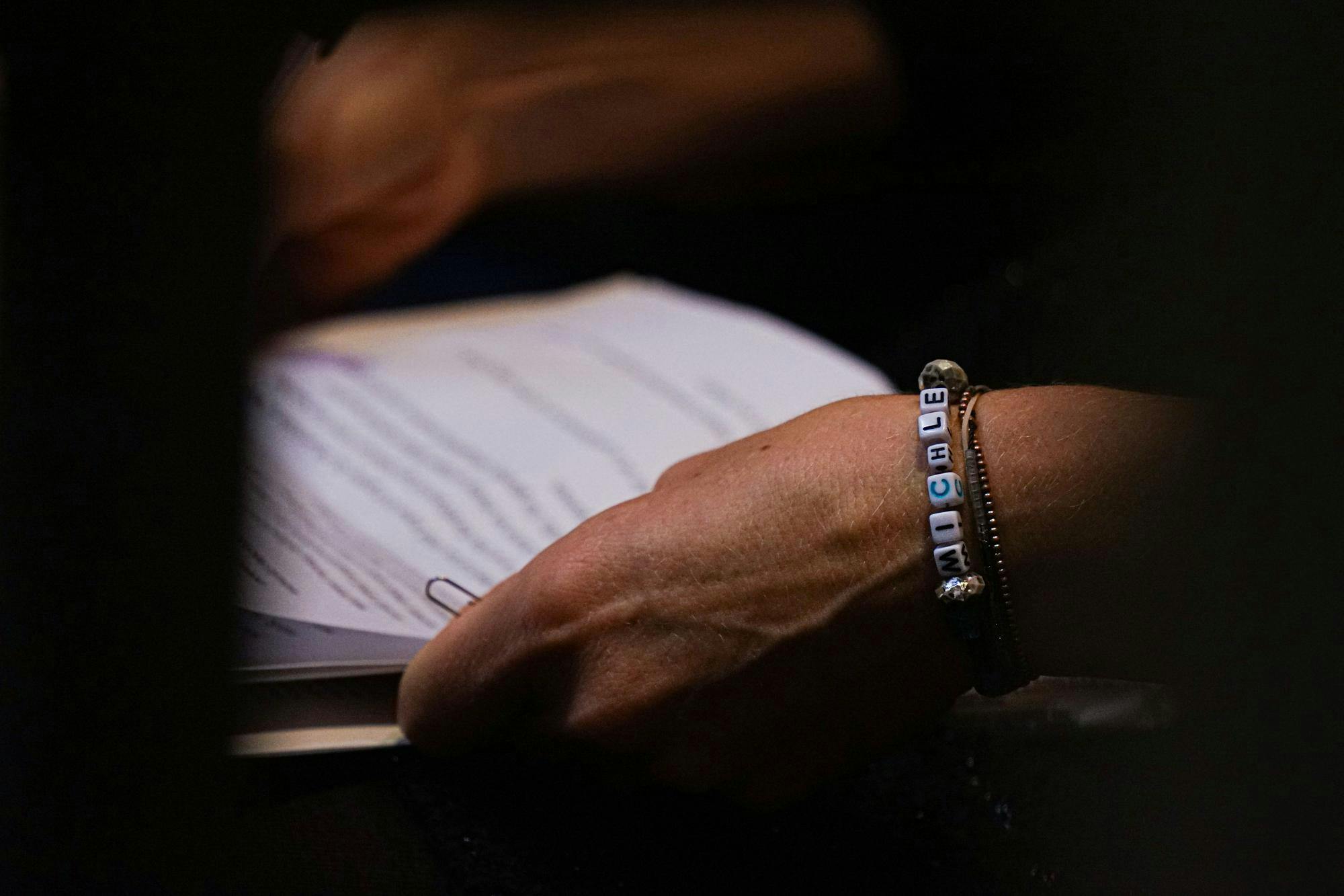 Kate Elliott, a lecturer for the School of Journalism and Strategic Communication at Ball State University, looks over her eulogy while wearing a bracelet bearing her husband's name. Elliott read the eulogy at the memorial for her late husband Michael Elliott, who was a coordinator for the musical theater program at Ball State's Department of Theatre and Dance. Michael's memorial was held Aug. 24, 2024, at the David and Mary Jane Sursa Performance Hall. Kate Farr, DN