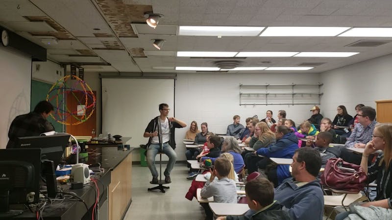 A student from the Society of Physics Students (SPS) teaches attendees Nov. 9, 2019, about rotational motion using a bike wheel and a stool at the "Clash of Sciences" event. SPS was one of three organizations at the event. Jaden Hasse, DN