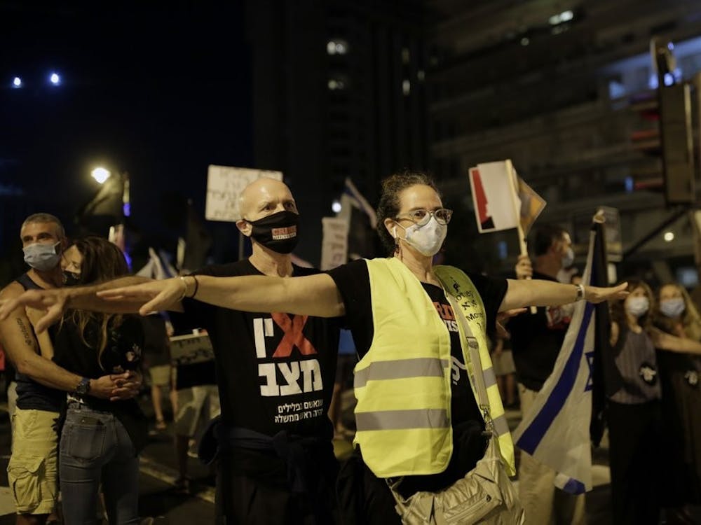 Protesters spread their arms to socially distance in the square outside of Prime Minister Benjamin Netanyahu's residence in Jerusalem, Saturday, Sept. 26, 2020, during a three-week nationwide lockdown in Israel to curb the spread of the coronavirus. (AP Photo/Maya Alleruzzo)