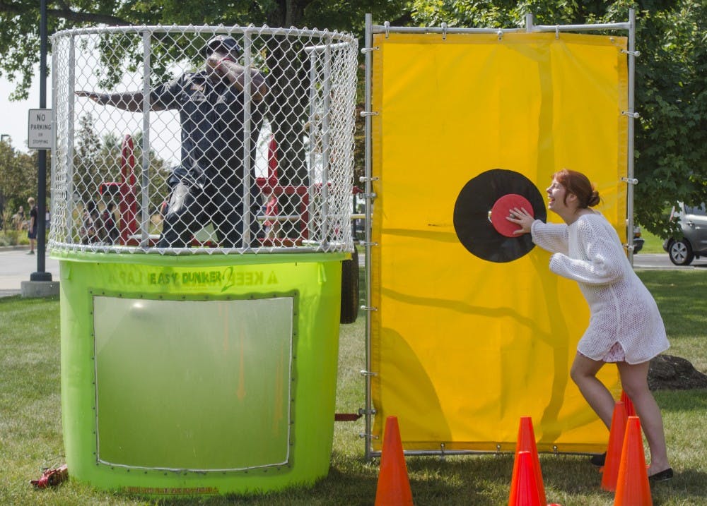 Senior psychology major Chyna Spencer presses the button to dunk Police Sergeant Terrell Smith at Dunk-a-Cop on Aug. 28 near the Scramble Light. DN PHOTO BREANNA DAUGHERTY