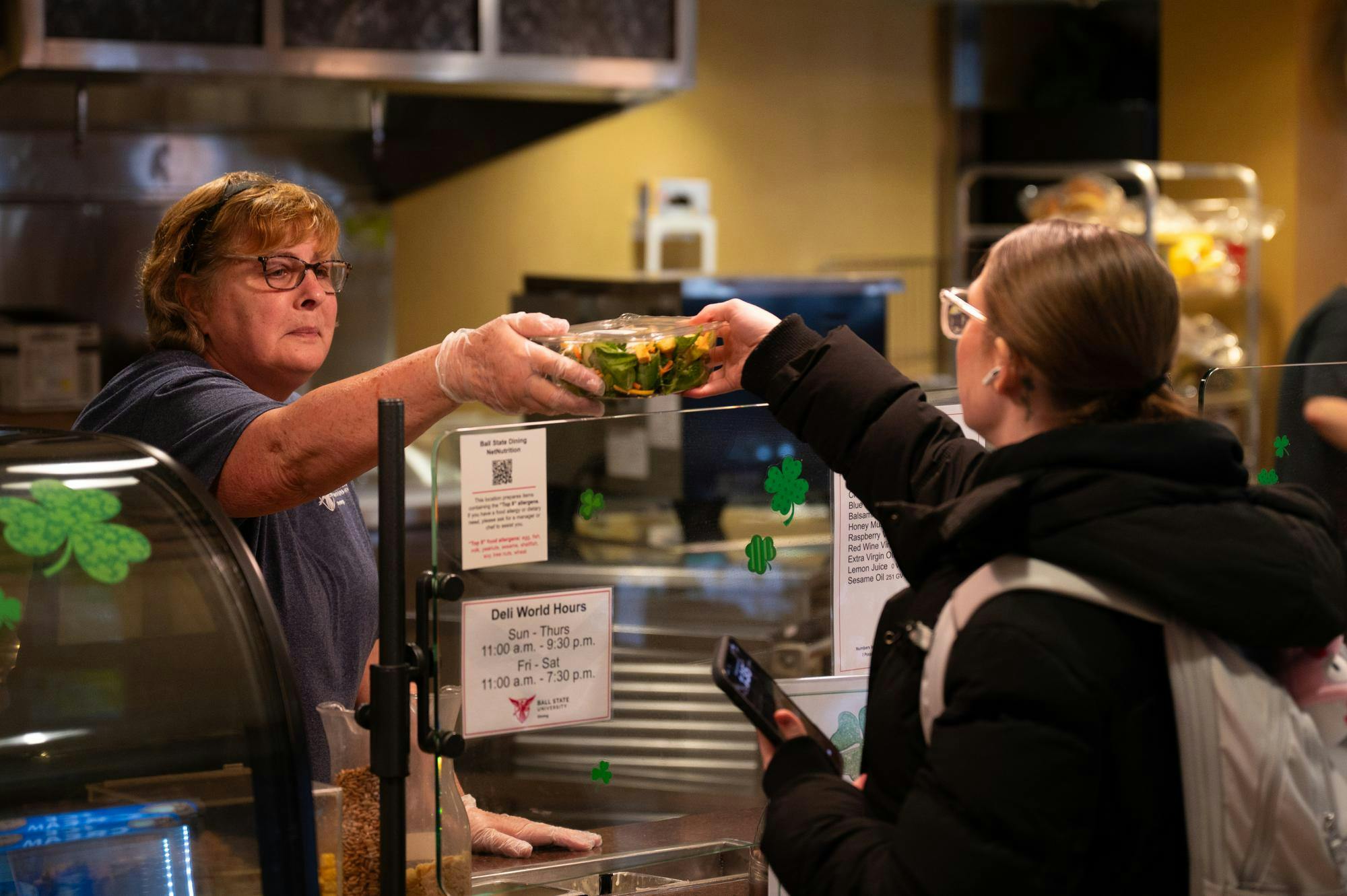 Ball State University Dining employee hands a student their meal during the Saint Patrick's Day Meal event March 17 in the Woodworth Dining Complex. Kadin Bright, DN